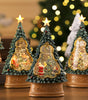 Decorative Christmas trees with glowing interiors on a wooden surface, blurred lights in the background.