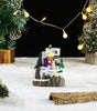 Miniature Christmas scene with a snowman, trees, and lights on a snowy background