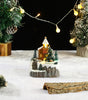 Miniature Christmas scene with a church, trees, and lights on a snowy base.