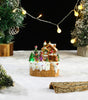 Decorative Christmas scene with a small house, trees, and lights on a snowy surface.