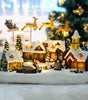 Christmas village scene with lit houses, trees, and Santa in a sleigh.