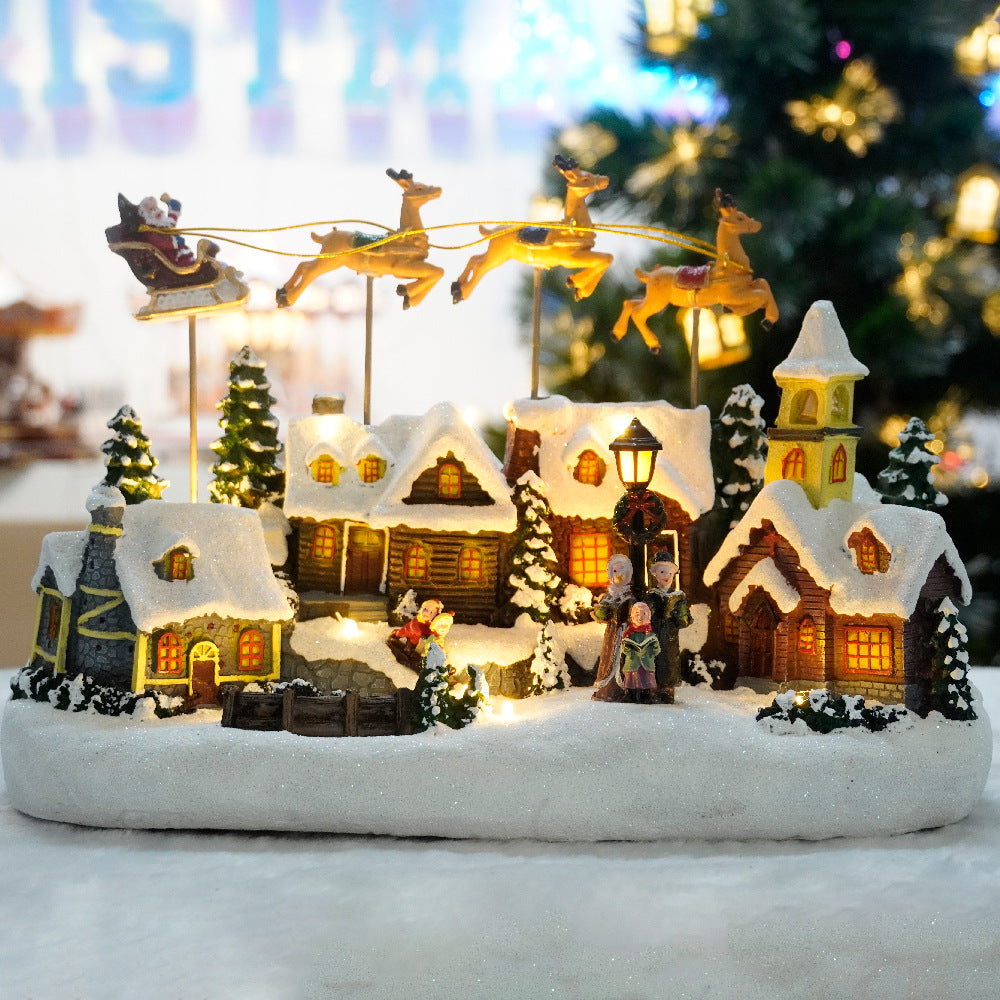 Christmas village scene with lit houses, trees, and Santa in a sleigh.