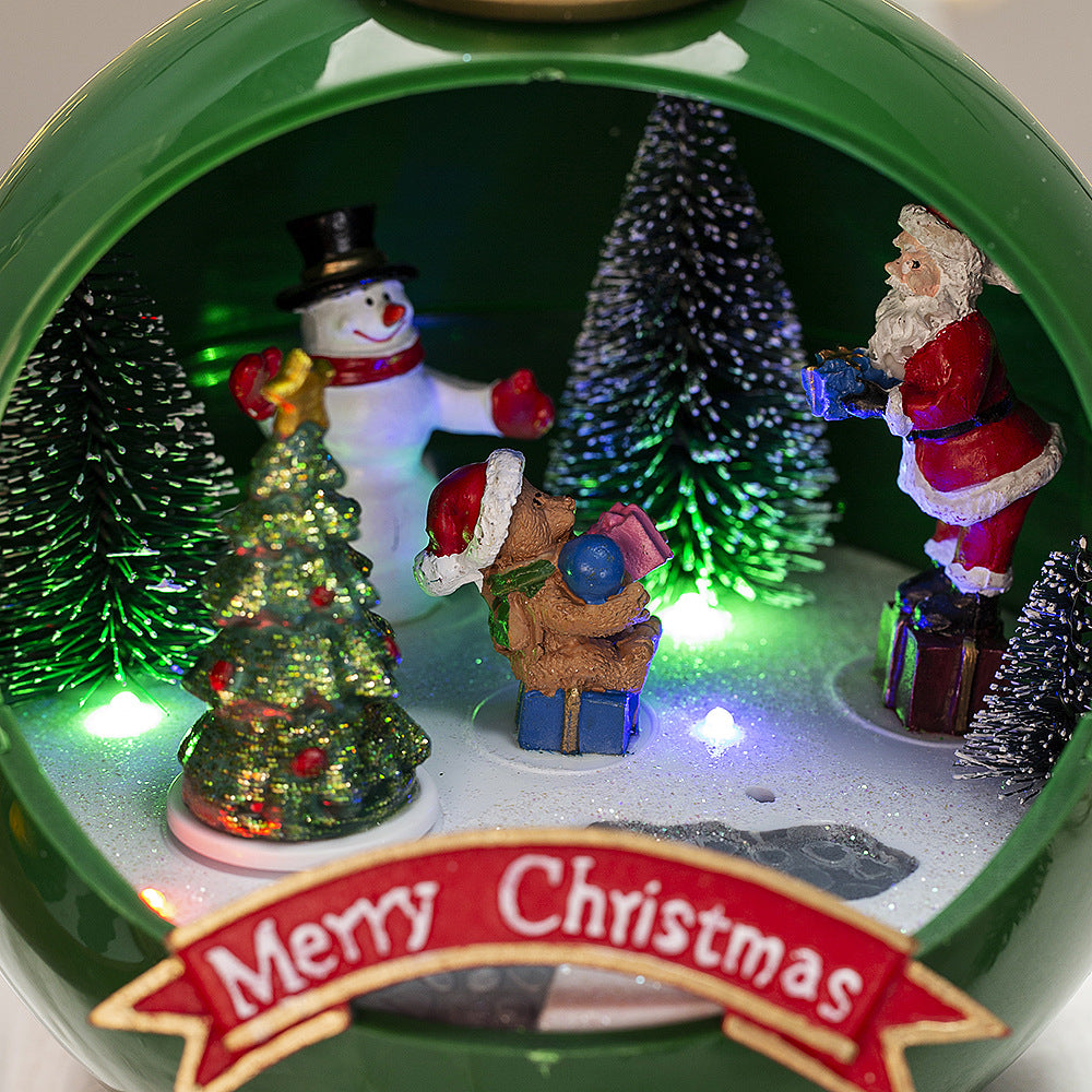 Christmas-themed miniature scene with Santa Claus, snowman, and trees inside a circular frame.