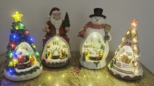 Four Christmas-themed light-up figurines on a wooden surface.