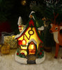 Decorative Christmas scene with a lit gingerbread house, reindeer, and presents.