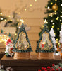 Two decorative Christmas tree figurines on a wooden stand with festive background.