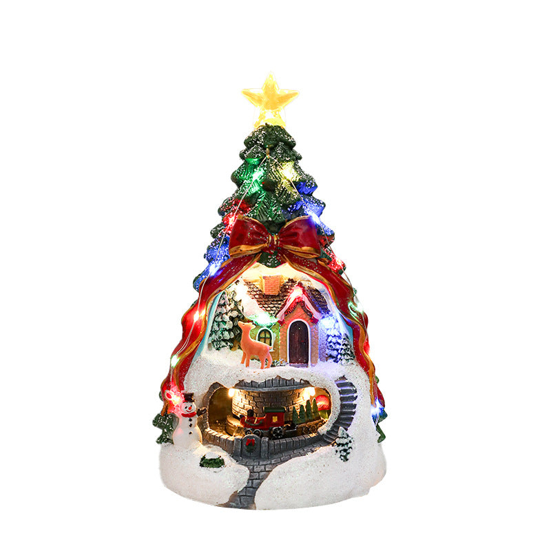 Decorative Christmas tree with lights and a house at its base on a white background