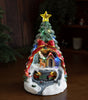Decorative Christmas scene with a lit-up tree, house, and reindeer on a wooden surface.