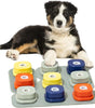 Dog interacting with a colorful paw-prints dog talking toy on a white background