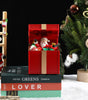 Decorative Christmas scene with a red gift box, Santa Claus figurine, and Christmas tree.