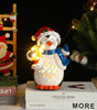 Decorative penguin lamp with string lights on books, surrounded by Christmas decorations.