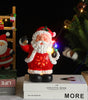 Decorative Santa Claus figure with lights on books, Christmas tree, and decorations in the background.