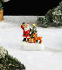 Miniature Santa and deer figure x a Christmas tree in a snowy scene.