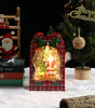 Decorative Christmas scene with a lit-up ornament, tree, and Santa Claus figure.
