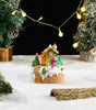 Miniature Christmas scene with a house, trees, and lights on a snowy background