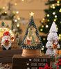 Decorative Christmas tree figurine with lights and Santa Claus, surrounded by festive decorations.