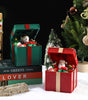 Decorative Christmas scene with open gift boxes, snowmen, and a Christmas tree.
