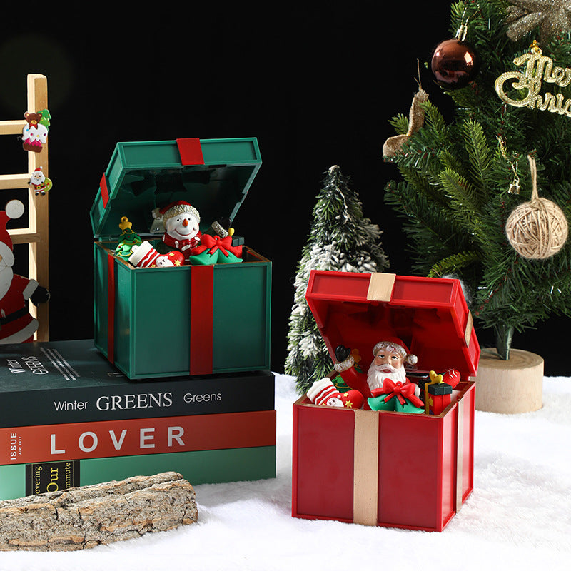 Decorative Christmas scene with open gift boxes, snowmen, and a Christmas tree.