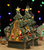 Decorative Christmas tree figurine with Santa Claus and snowmen inside, on a wooden surface with blurred lights in the background.