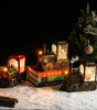 Decorative train set with lights on books next to a Christmas tree.